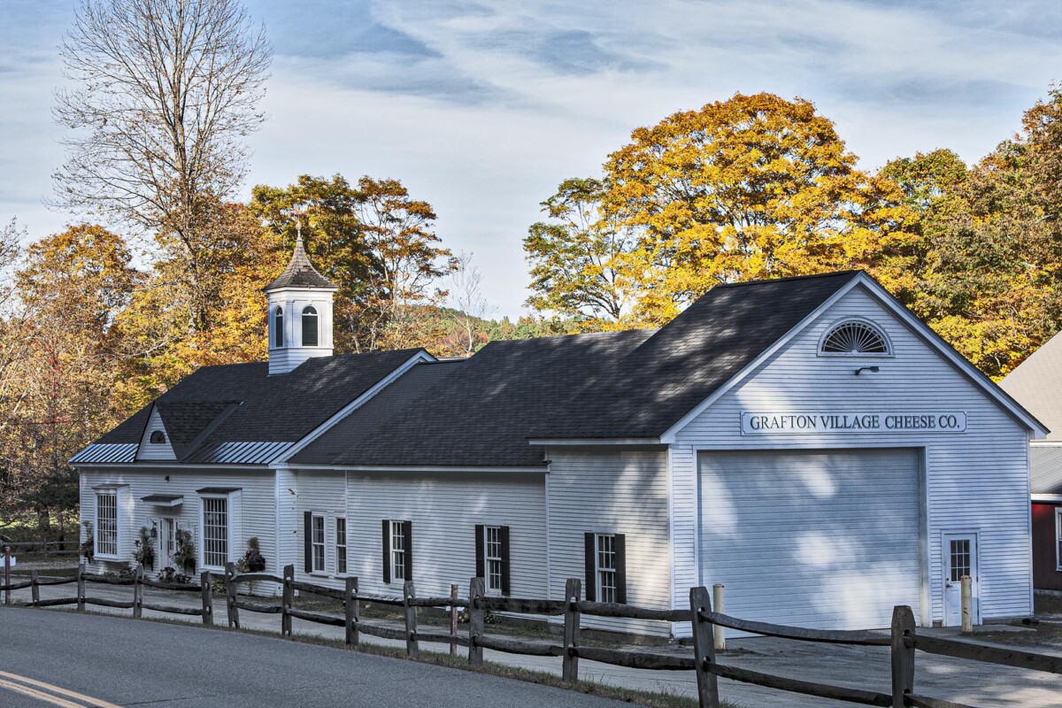 white clapboard building with black roof and shutters