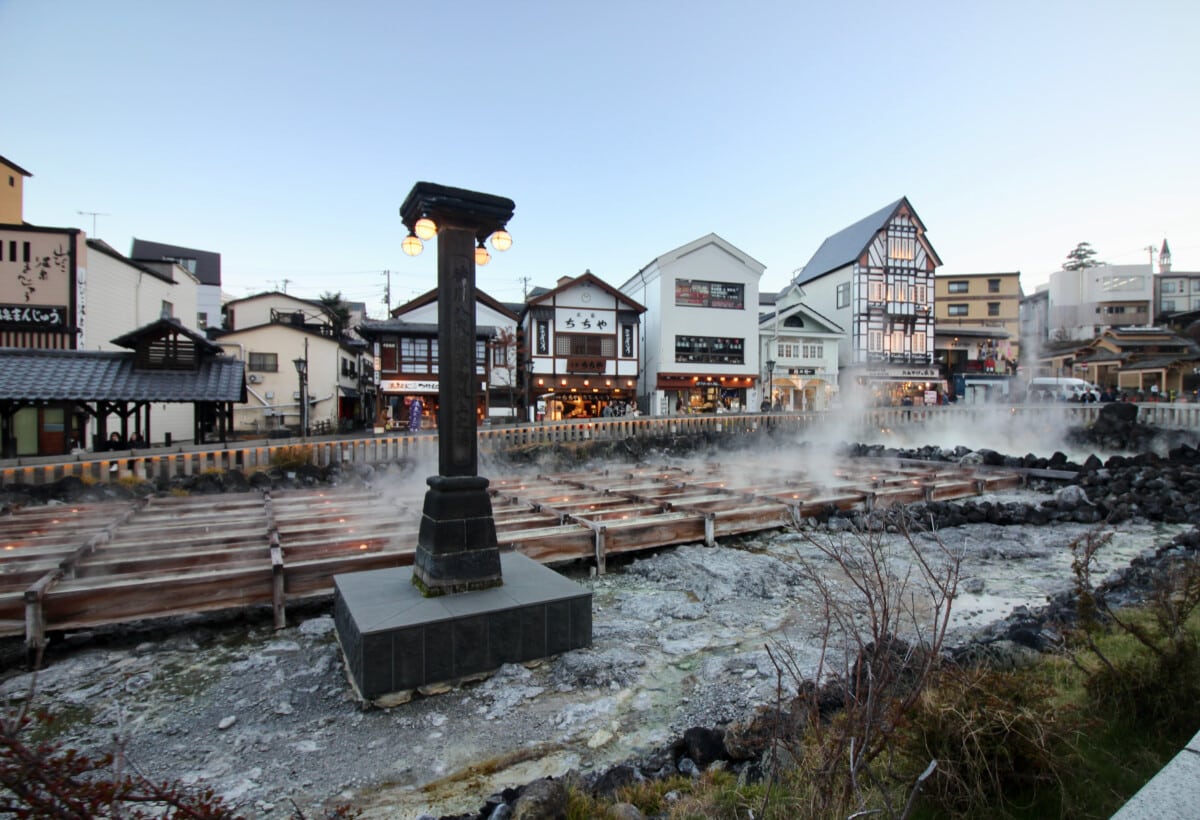 Kusatsu Yubatake at dusk lights up with the glow of local shops turning on their yellow-orange lights.