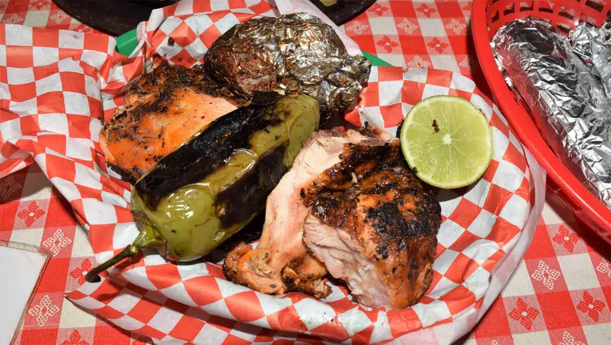 The half chicken plate with a grilled onion, a grilled jalapeño pepper, corn tortillas, and salsa.Photo courtesy of Pollos Asados Los Norteños
