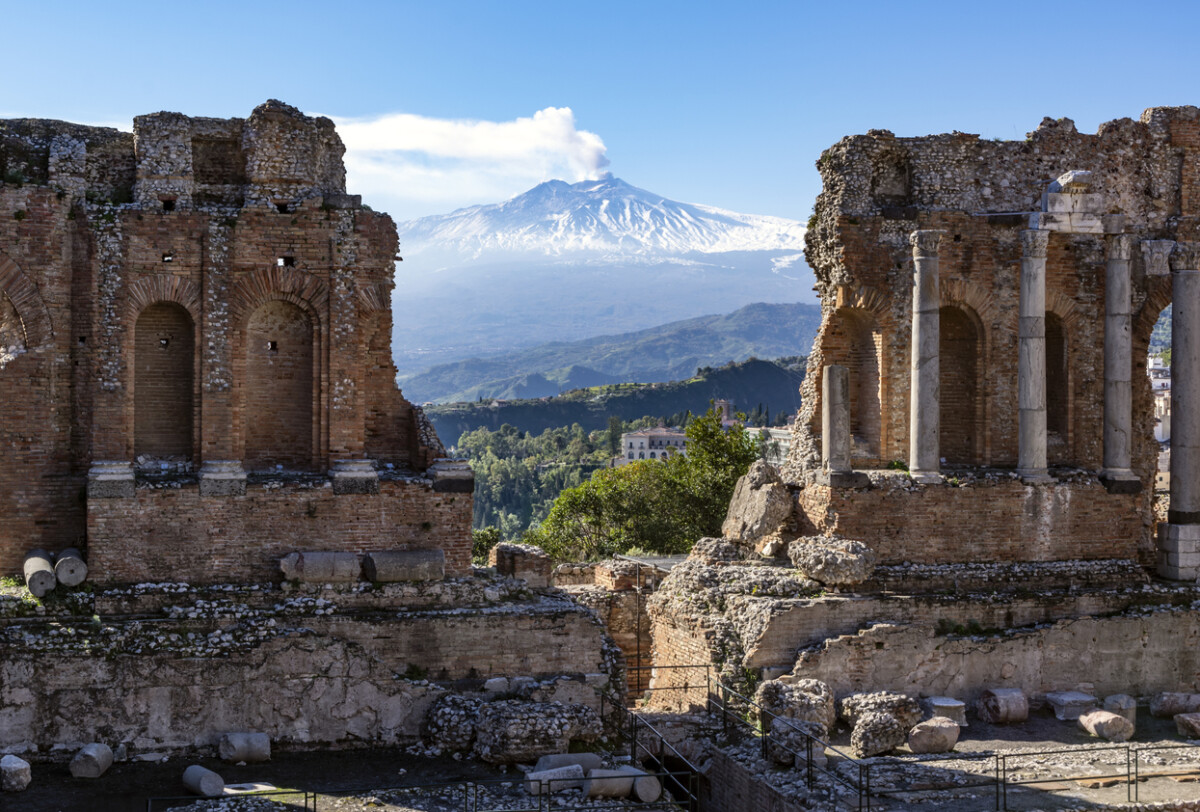 Volcano Etna in Sicily seen through ruins of ancient amphitheater in Taormina. Photo by Stefan_Alfonso via iStock by Getty Images