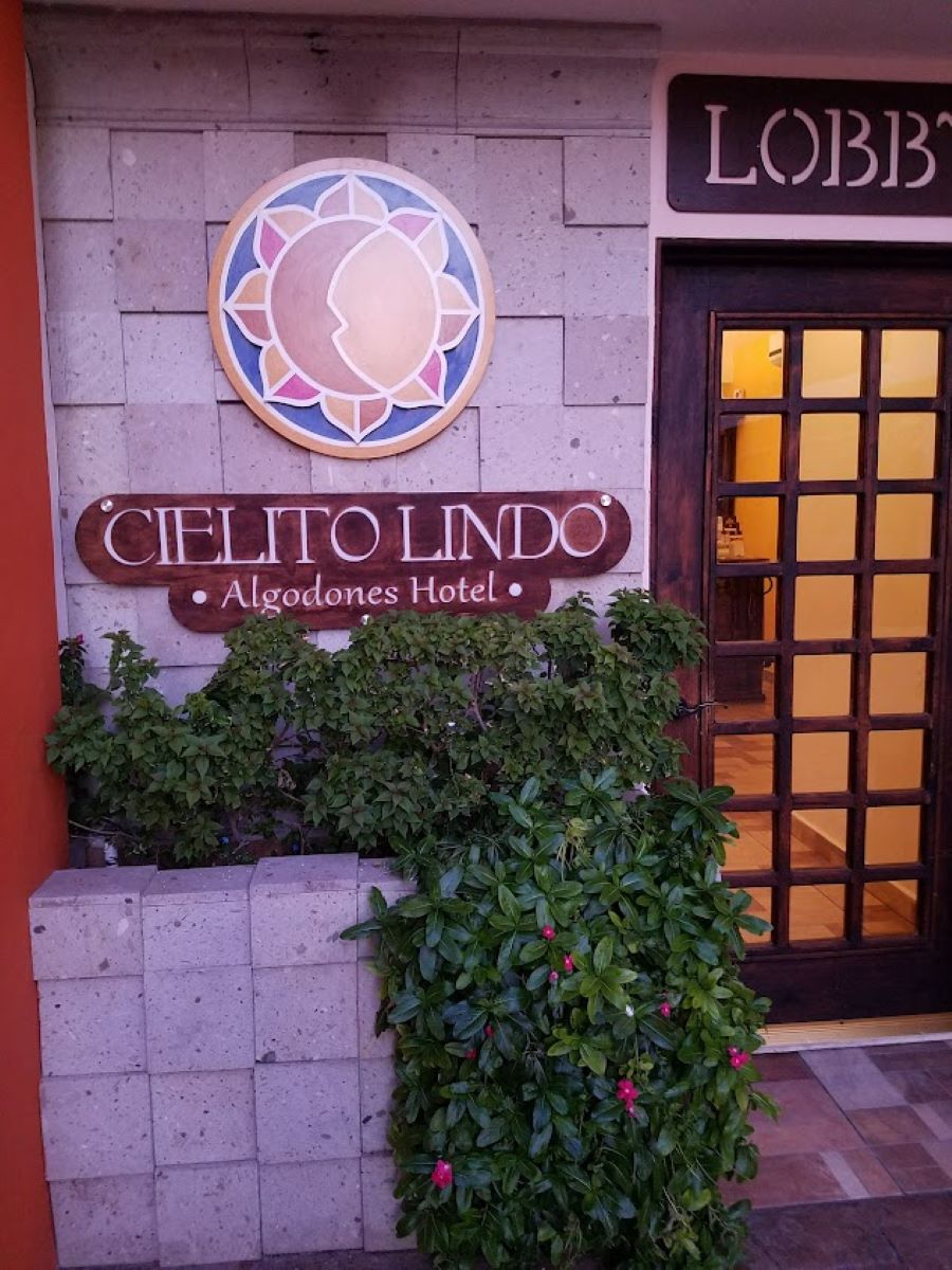 The entrance sign to the Cielito Lindo Hotel with flowering plant below it.