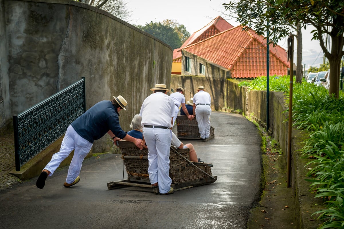Toboggan riders moving traditional cane sledge downhill on the streets of Funchal. Monte park, Madeira island, Portugal