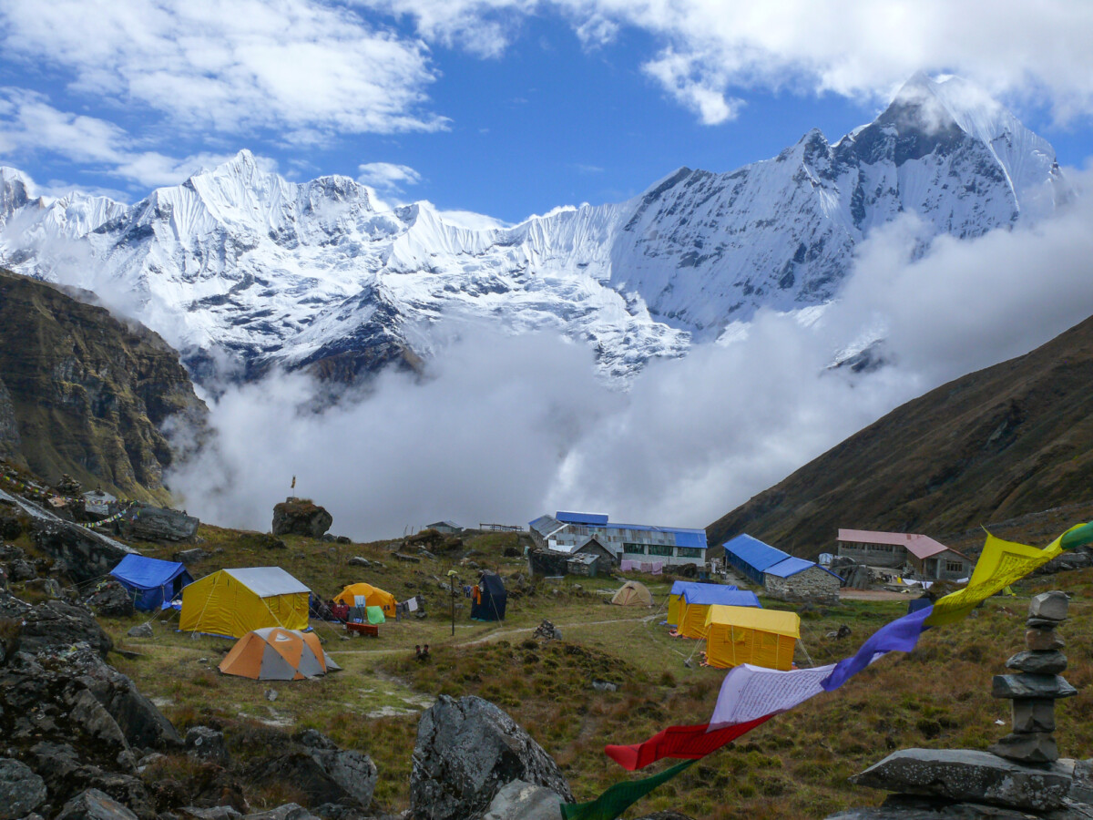 The Best Ways to Enjoy Adventures in Nepal 4 Tents in Annapurna Base camp with a view of Mount Machapuchare. Photo by strobl.r via DepositPhotos