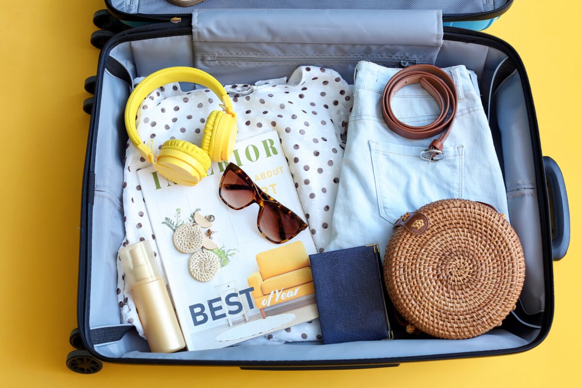 Packed suitcase with belongings on color background. Travel concept