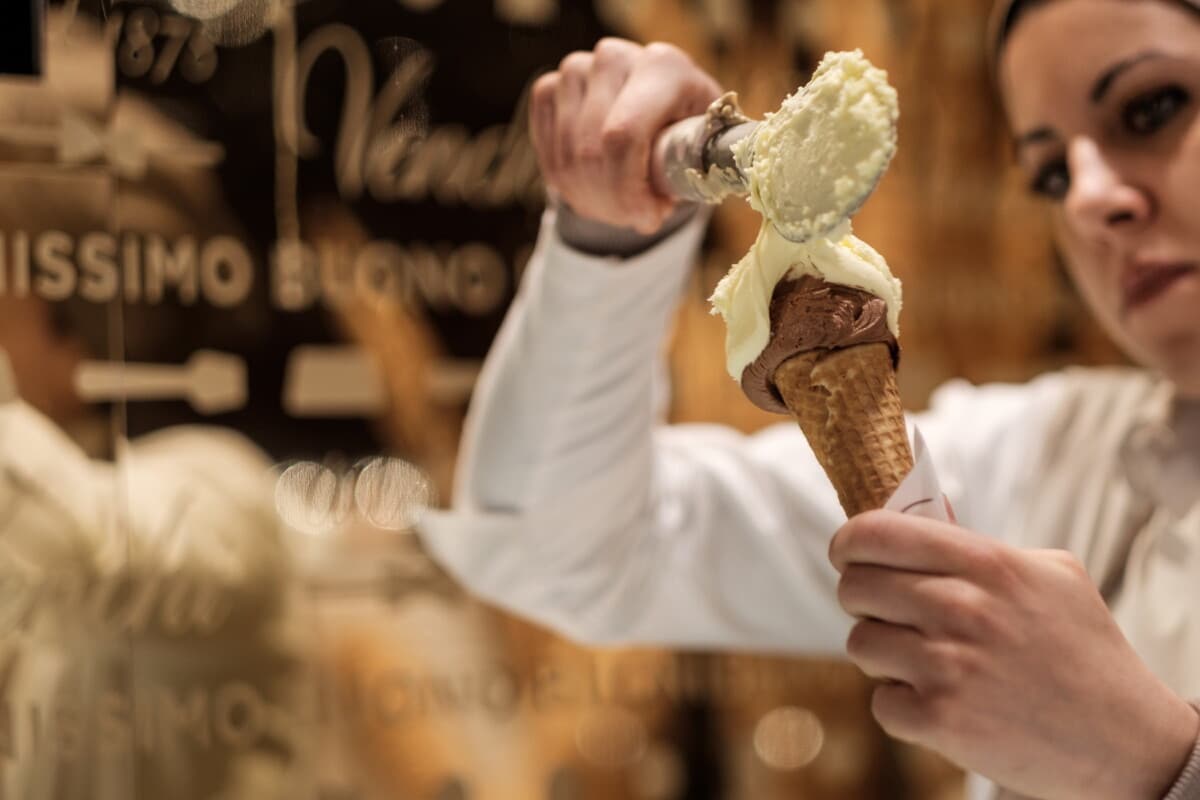 A server scooping gelato into a cone, Italy.
