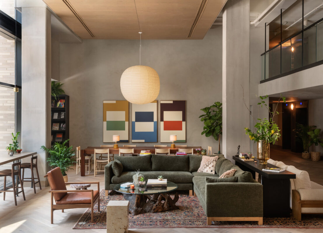 Hotel lobby with mid-century modern furniture, plants, and colorful geometric art on the wall