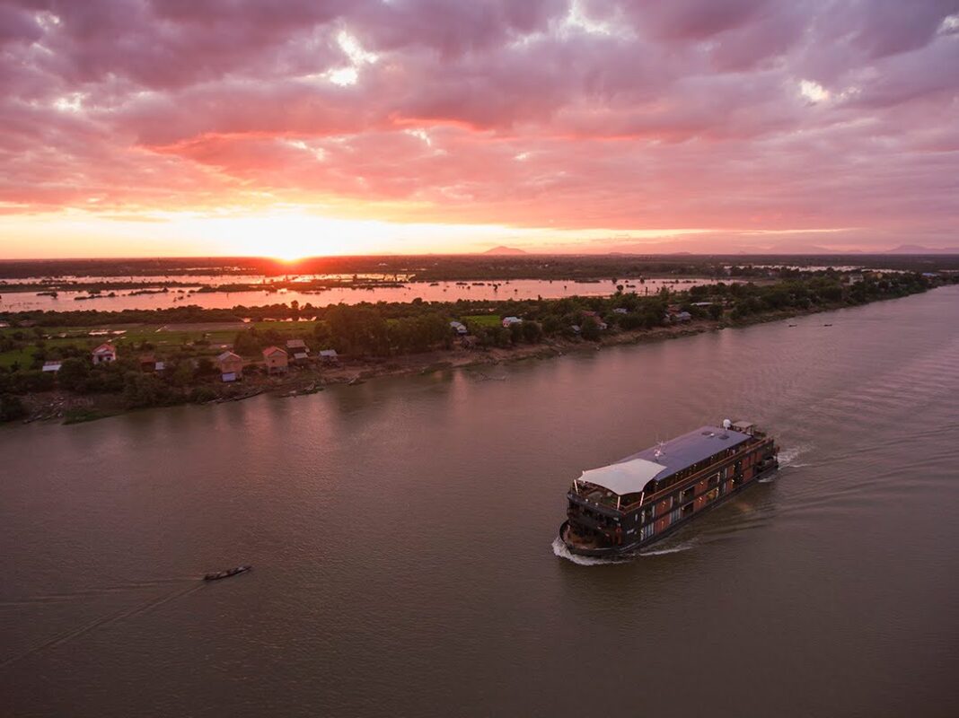 Aerial of river cruise ship Aqua Mekong (Aqua Expeditions) cruising on Tonle Sap river at sunset, Kampong Tralach, Kampong Chhnang, Cambodia