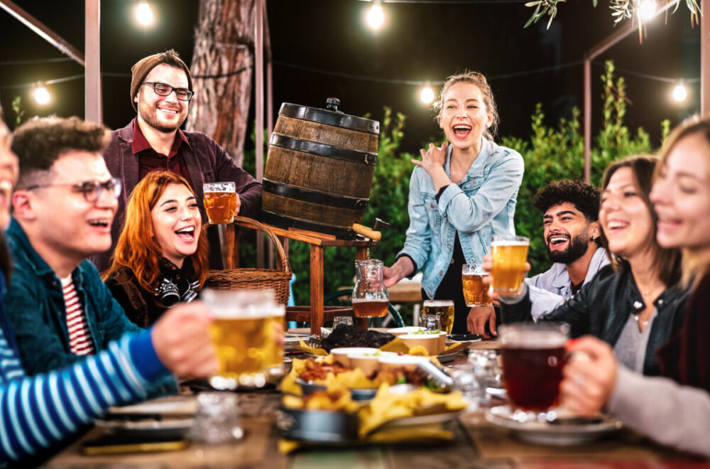 Destination Nightlife: How to Plan Your Evenings Before You Travel 3 Happy men and women having fun drinking out at beer garden - Social gathering life style concept on young people enjoying hangout time together at night - Warm filter with shallow depth of field