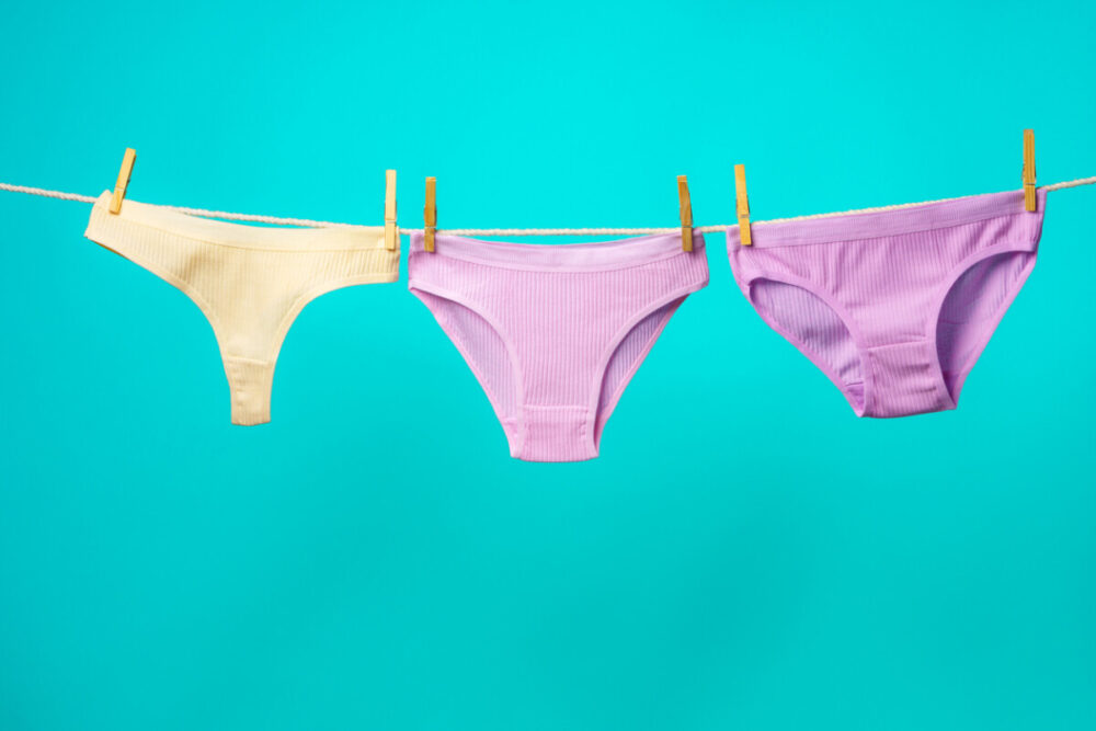 Finding the Perfect Thongs and Underwear for Backpacking 1 Female panties hanging on rope against blue studio background copy space