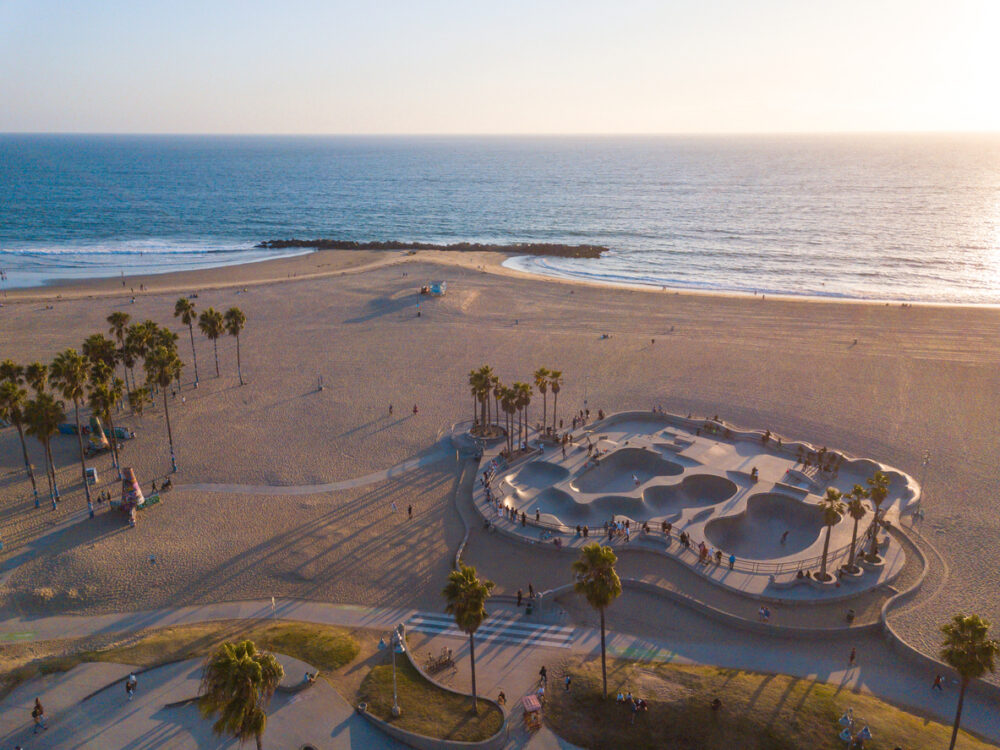 Exploring Los Angeles: What to Expect When Visiting the City of Angels 3 Aerial photos of the Venice Beach Skate Park taken with a drone during sunset. Long shadows of palm trees and skateboarders.