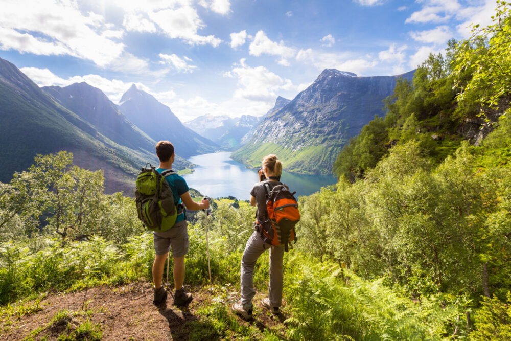 Finding the Perfect Thongs and Underwear for Backpacking 2 Two hikers at viewpoint in the mountains enjoying beautiful view of the valley with a lake and sunny warm weather in summer, green trees around