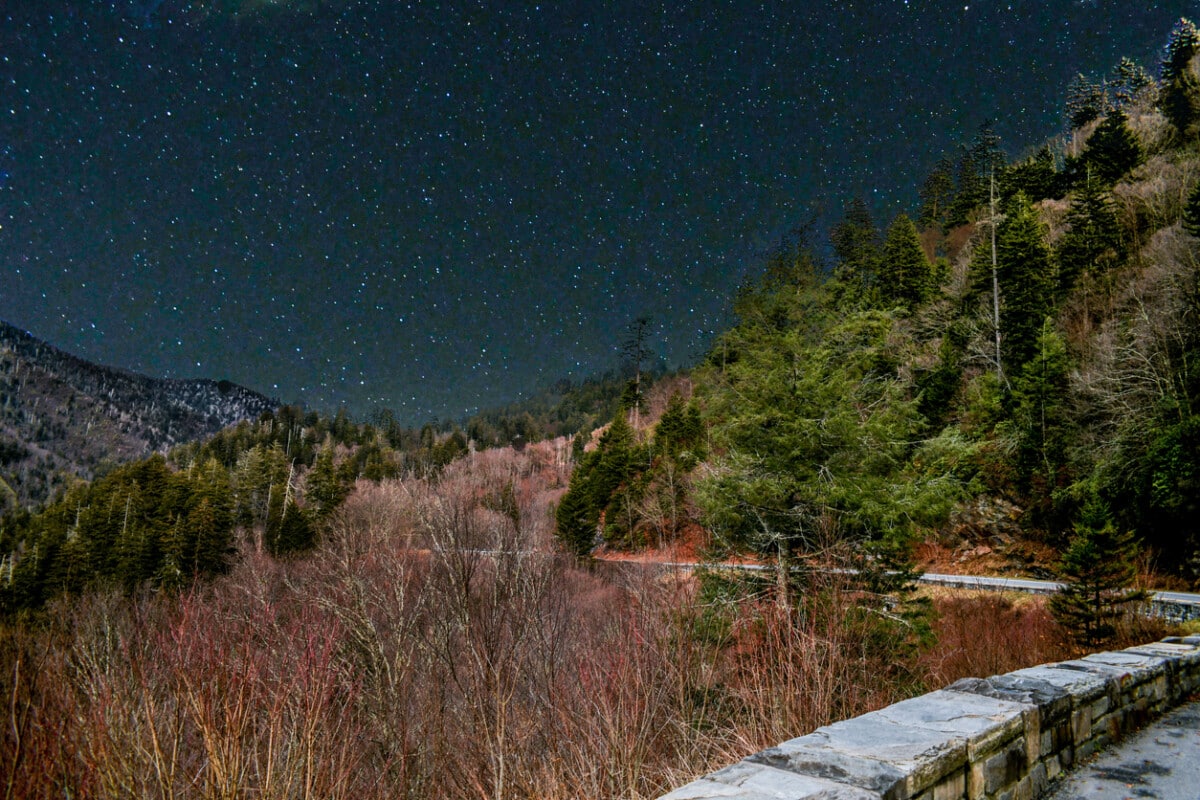 Scenic view of mountains with a star filled night time sky backdrop.