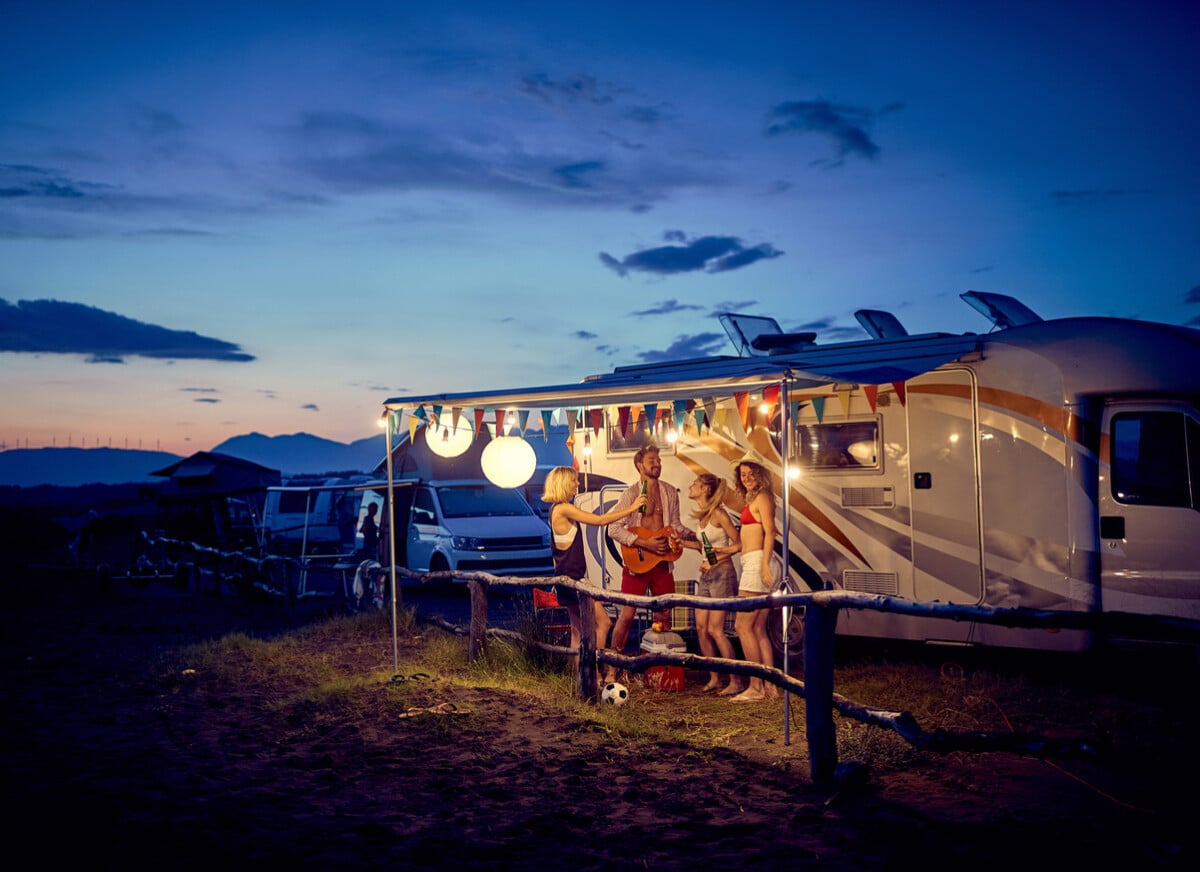 group of young friends enjoys a drink at a vacation at the campsite in the nature.