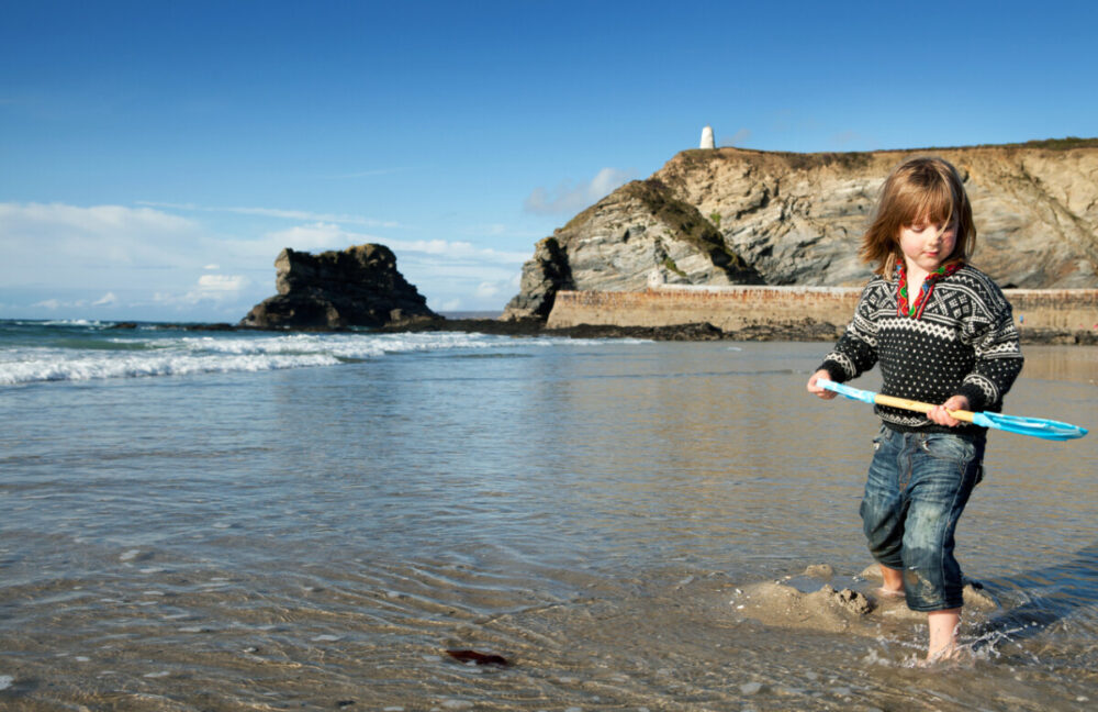 Child on beach in cornish harbour playing with sand and. St Agnes beach in Cornwall