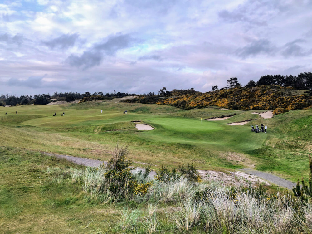 Golfing Through the Seasons: Year-Round Golfing in the US 3 A beautiful view of a parkland area with a par 4 golf hole in Bandon, Oregon, with the ocean in the background and yellow heather in bloom