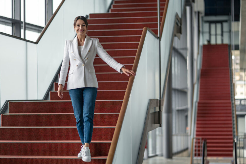 Boardroom Ready: Smart Packing Tips for Your Business Travel Wardrobe 2 In the office center. Pretty business woman in white jacket going down the stairs