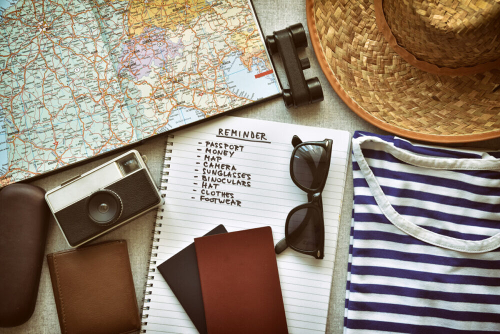 How to Plan an Unforgettable Honeymoon Abroad 1 Top view of traveler's accessories and travel checklist. Vintage style photo filter with grain and vignette added. Unforgettable honeymoon abroad.
