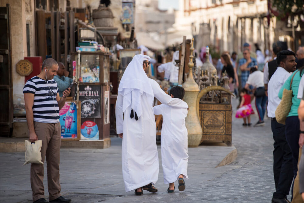 Qatari family in traditional attire hang out in old bazaar market Souk Waqif.