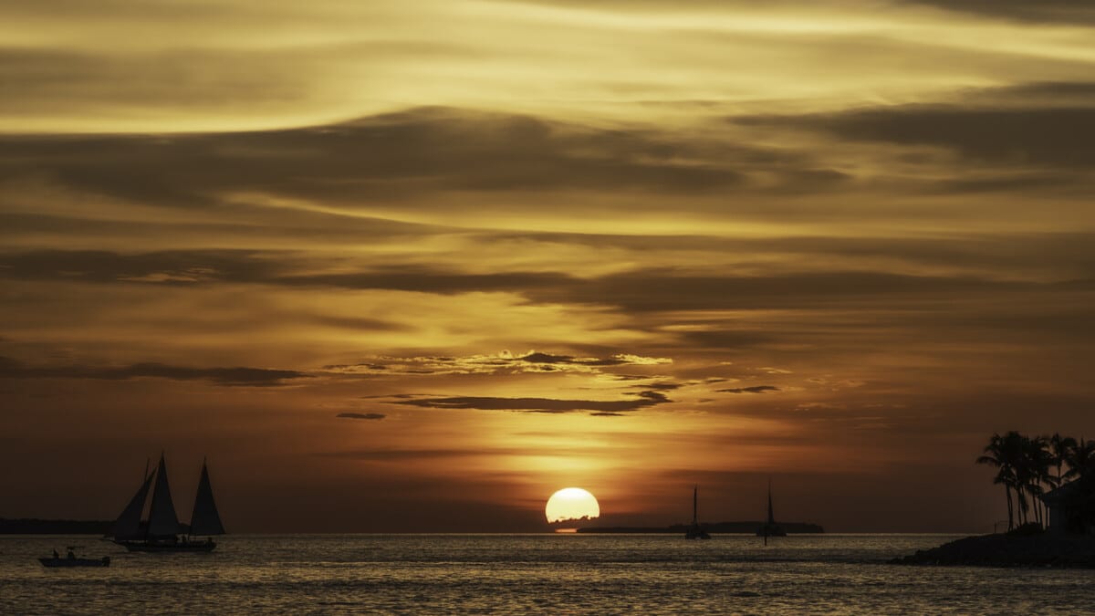 A spectacular sunset, off the coast of Key West, Florida, with sailing boats silhoutted against the orange sky