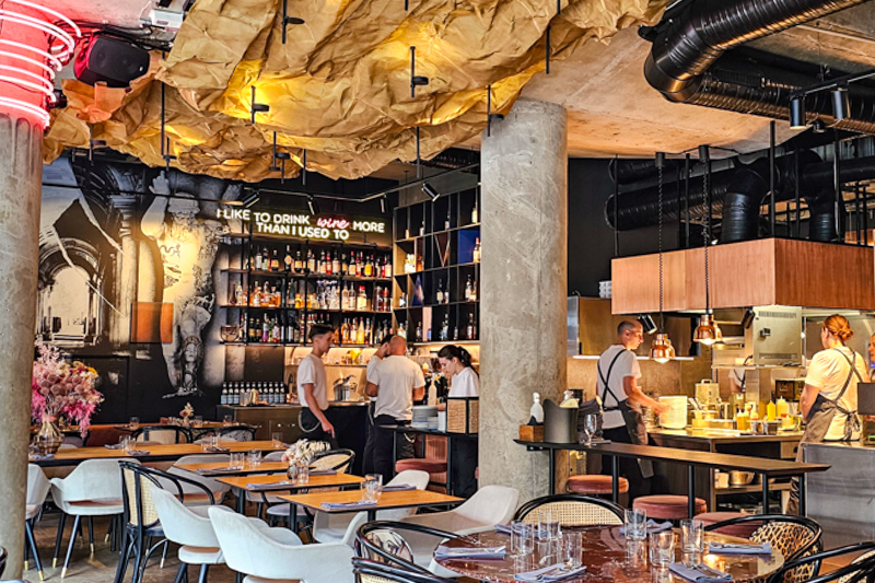 Interior of Snatch with open kitchen, tables, and wine wall.