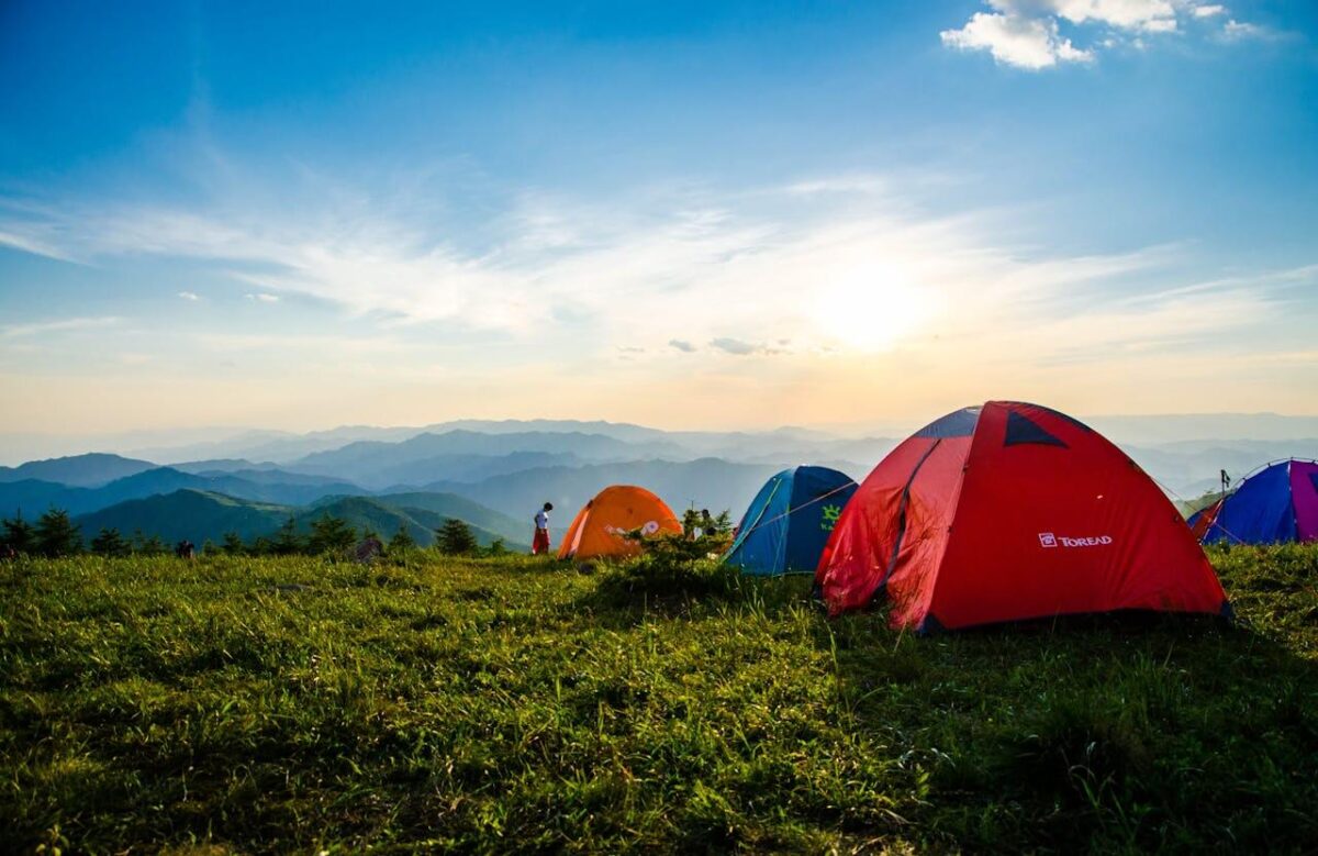 adventure camping with tents in a field overlooking mountains