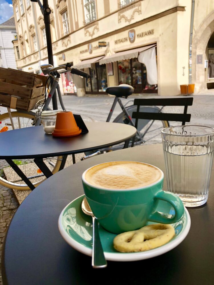 coffee shop in Krems, Austria a cup of coffee sitting on an outside table with a bike nearby