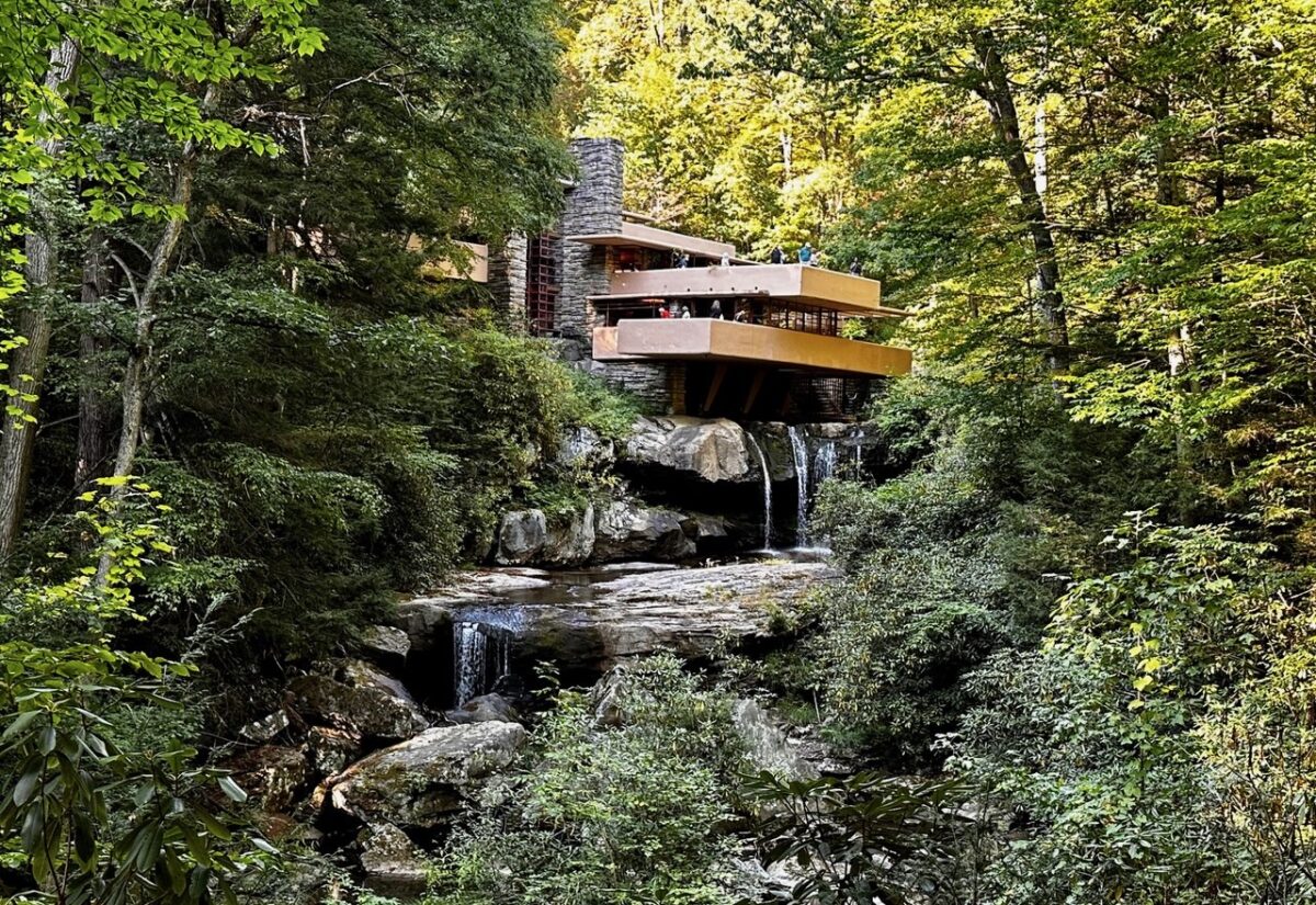 Fallingwater: A house with orange terraces and large stones with waterfall cascading from underneath.
