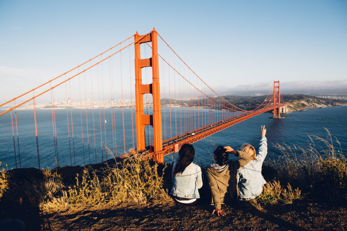 Rear View Of Women Sitting Against Golden Gate Bridge