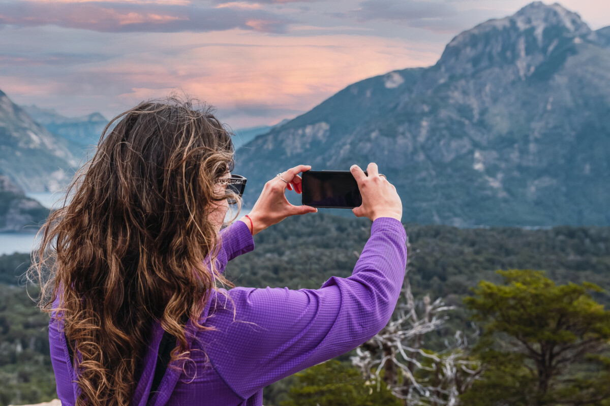 latin woman photographing landscape with mobile