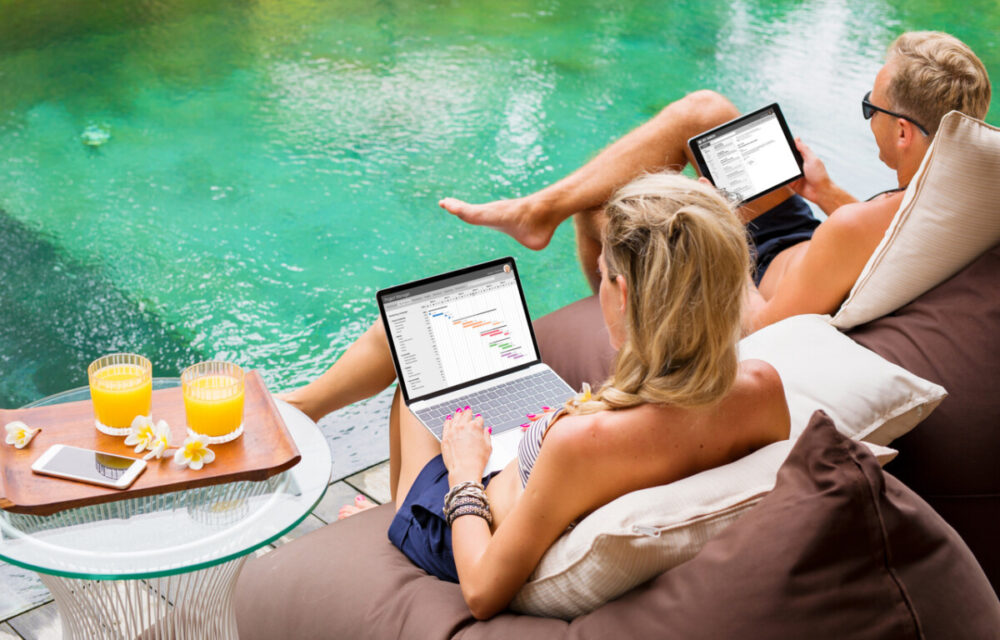 9 Productivity Tips for Digital Nomad Writers 3 Couple working on computers while relaxing by the pool.