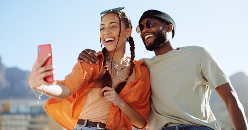 The Sophisticated Nomad: Curating Digital Safety for Global Adventures 3 Couple, bonding and phone selfie on city building rooftop on New York summer holiday, travel vacation date or social media memory. Smile, happy or black man and woman on mobile photography technology