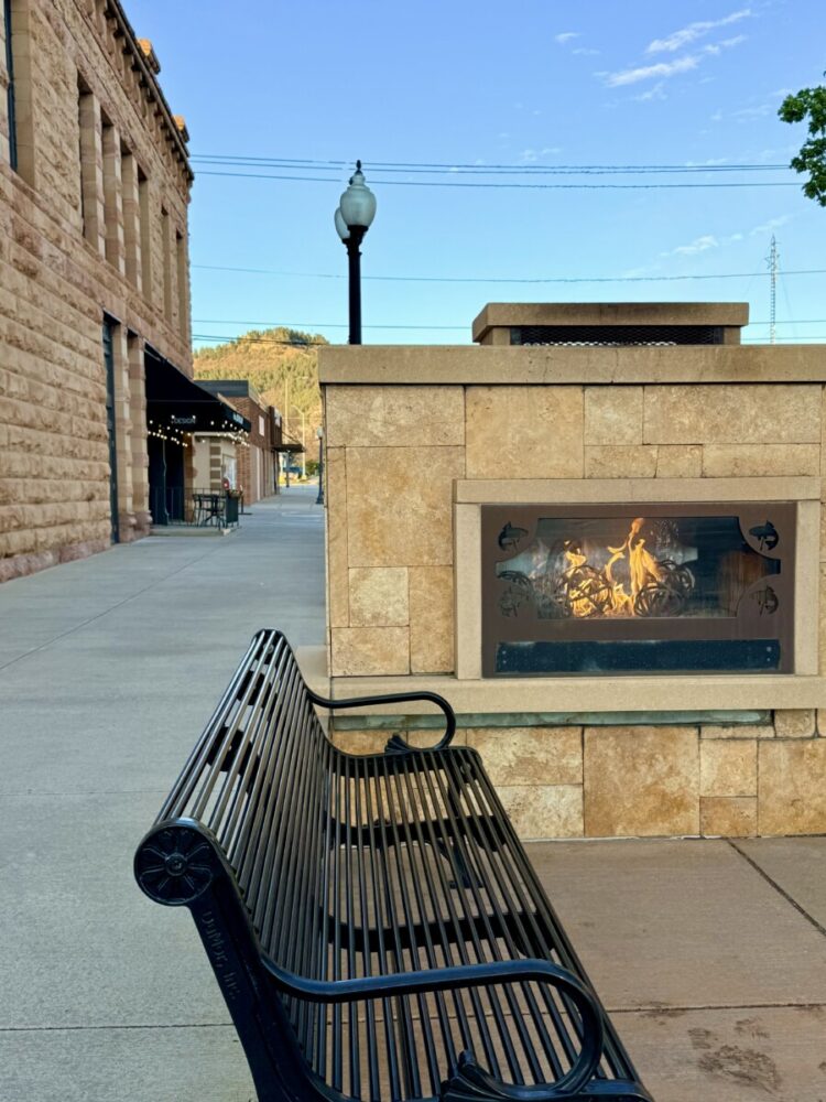 Black Hills, South Dakota Summer Travel Guide: Best Things to Do and Where to Go 19 fireplace burning with a bench on a street corner