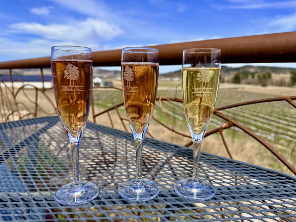Black Hills, South Dakota Summer Travel Guide: Best Things to Do and Where to Go 36 3 glasses of sparkling wine on a table overlooking the vineyard