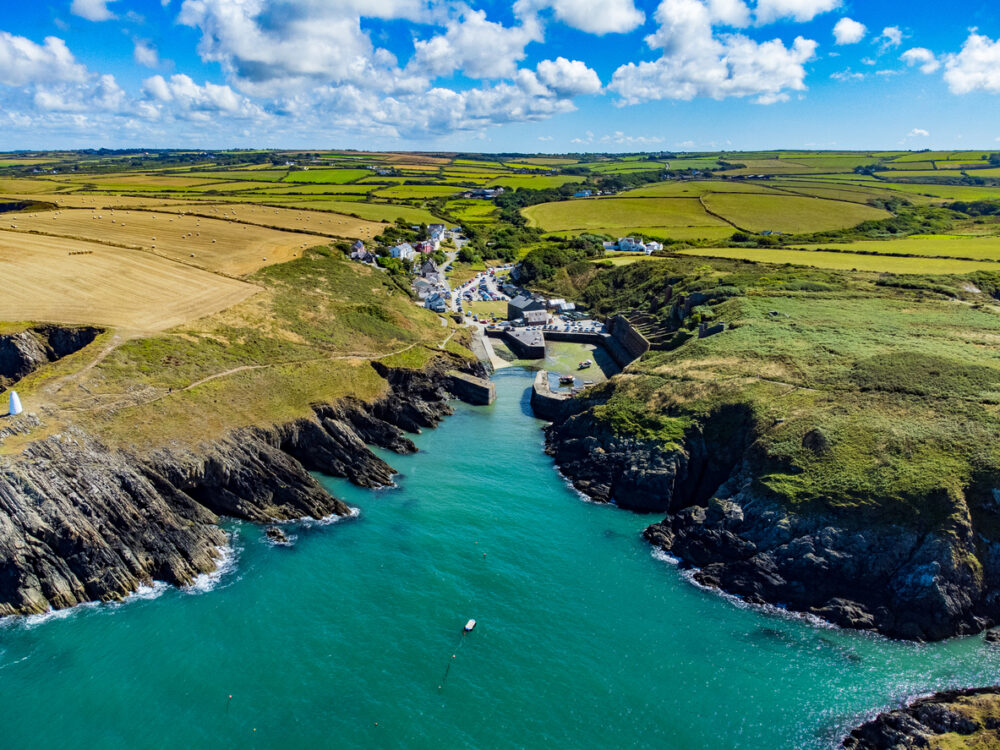 Best Scenic Coastal Escapes in the UK for Unforgettable Views 2 Discover the timeless charm of Porthgain Harbour in Pembrokeshire from a captivating aerial view. The drone reveals a picturesque harbor nestled between rugged cliffs, with fishing boats and historic buildings making it one of the most scenic coastal escapes in the UK. Immerse yourself in the coastal beauty and maritime heritage of Porthgain from above.