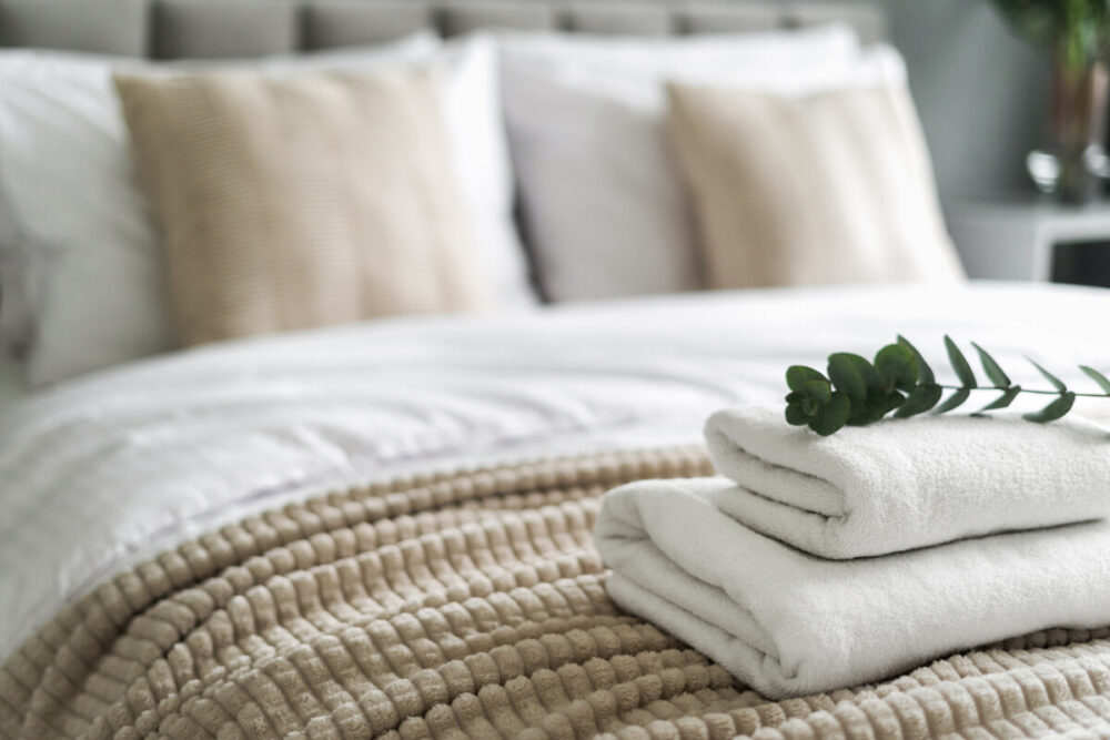 Why Hotel Beds Feel Better Than Your Bed (And How to Recreate the Comfort at Home) 1 White and fresh neatly folded towels on hotel bed