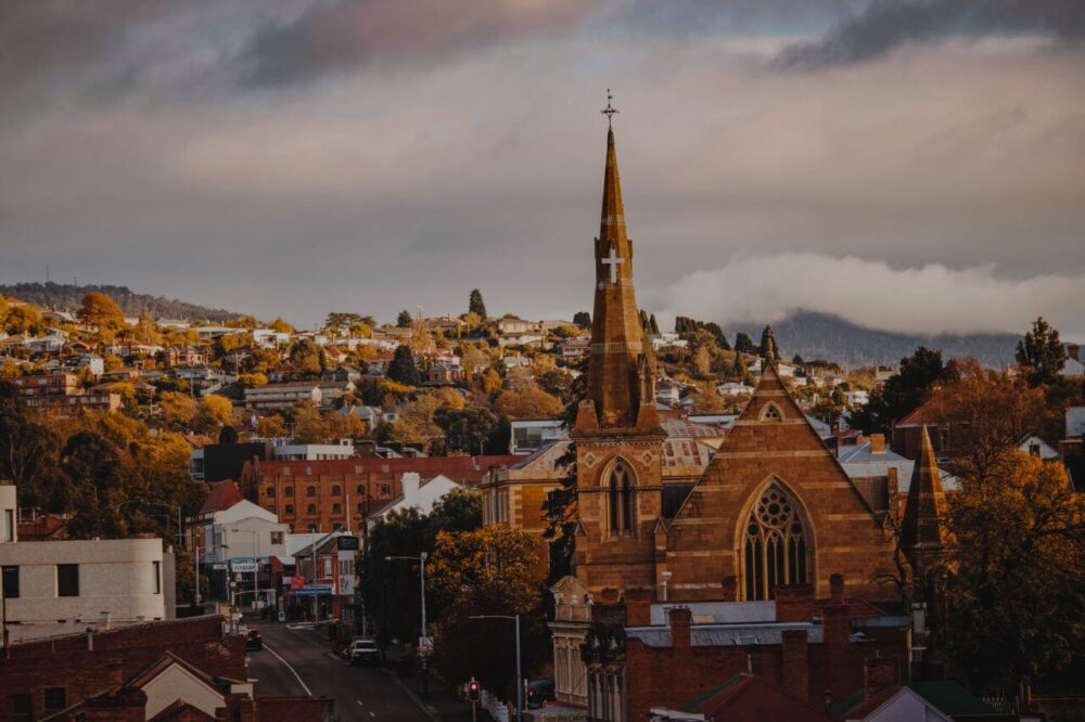 Hobart Food Guide: 10 Things to Eat, Drink, and Do in Tasmania 9 A picturesque view of a historic church and townscape in Hobart, Tasmania with a moody backdrop