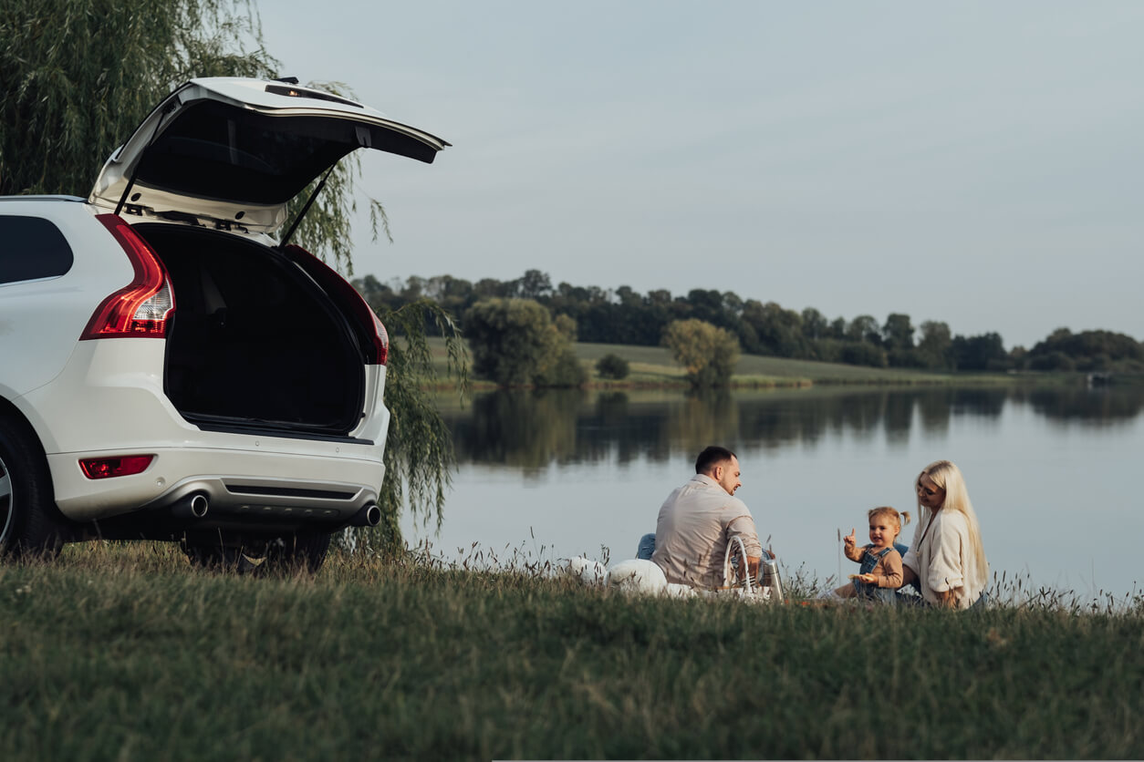Happy Young Family Enjoying a road trip Picnic by a pond
