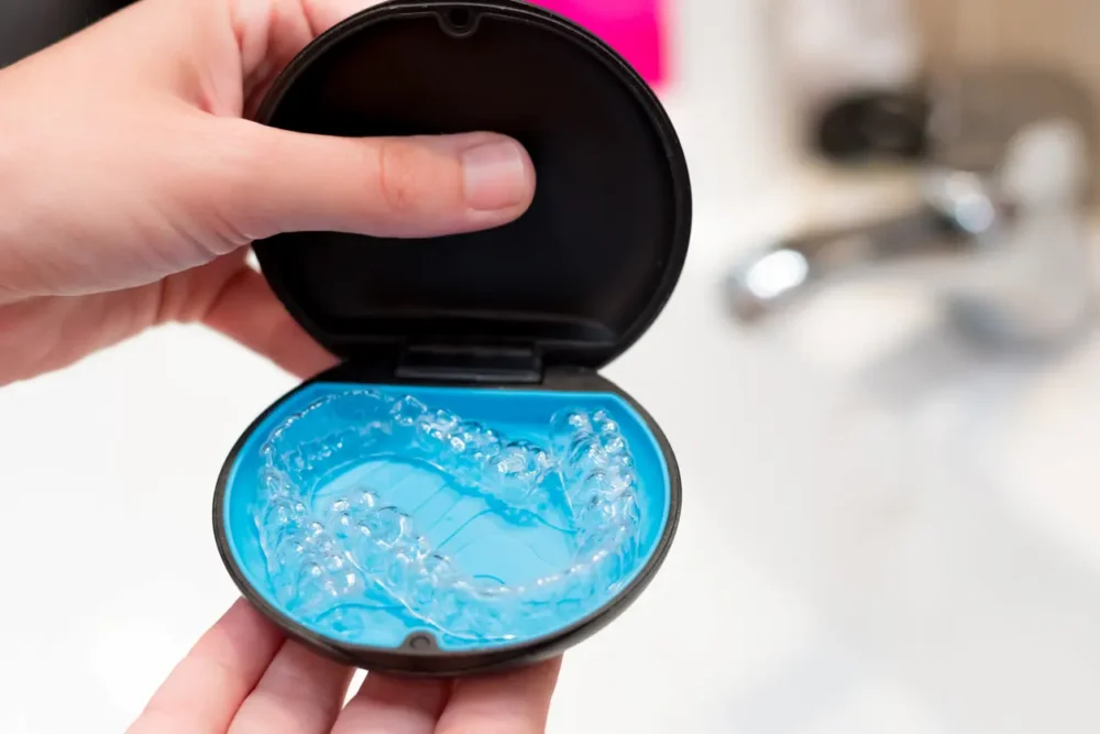 How to Manage Traveling With Clear Aligners Like a Pro 1 woman's hand holding a case with invisible aligners for dental correction