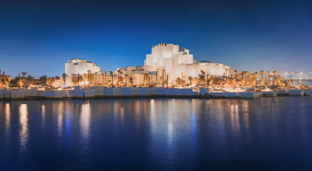 8 Helpful Resources for Planning a Saadiyat Island Trip 1 Iconic new Natural History Museum building on Saadiyat island, reflecting its distinctive modern architecture and warm lights on the calm water of Arabian Gulf