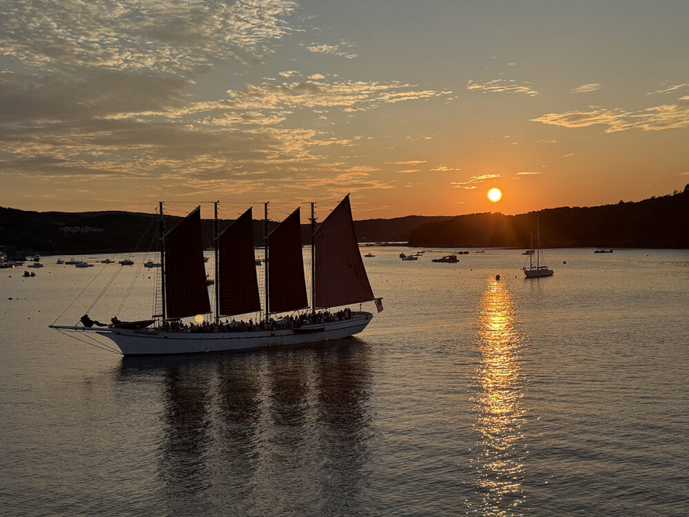 Explore Maine's Coast and Harbors Aboard American Cruise Lines 32 A ship on the water during sunset from our ship in Bar Harbor, Maine