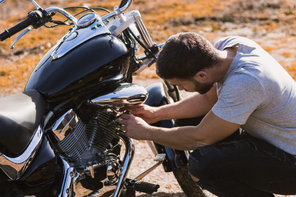 Crouching biker worried about a motorcycle