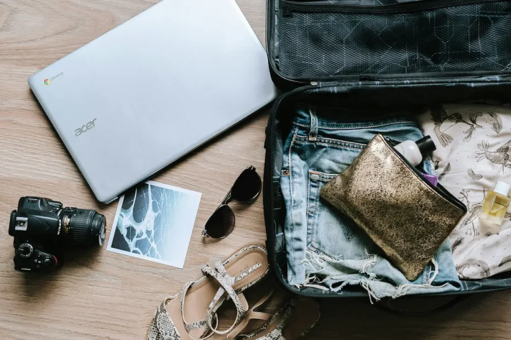 How to Build a Travel Capsule Wardrobe With an AI Stylist 3 DSLR camera, a laptop, and a suitcase