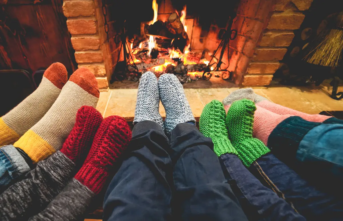 Five sets of stocking feet stretching out to feel the warmth of a fireplace