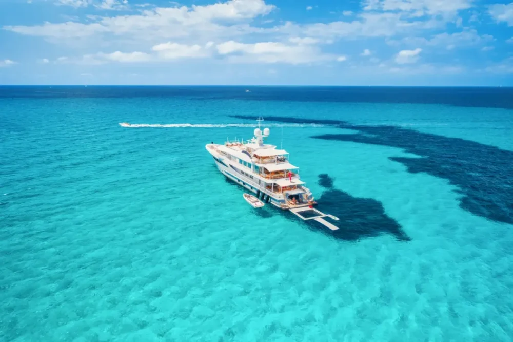 Beyond Traditional Cruises: Small-Ship Cruises and Specialty Sailings 4 Yacht on the azure seashore in balearic islands. Aerial view of floating boat with people in transparent sea at sunny day in summer. Top view from drone. Seascape with luxury yachts in motion in bay